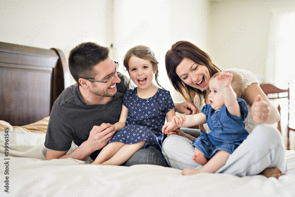 happy family mother, father and two children at home in bed