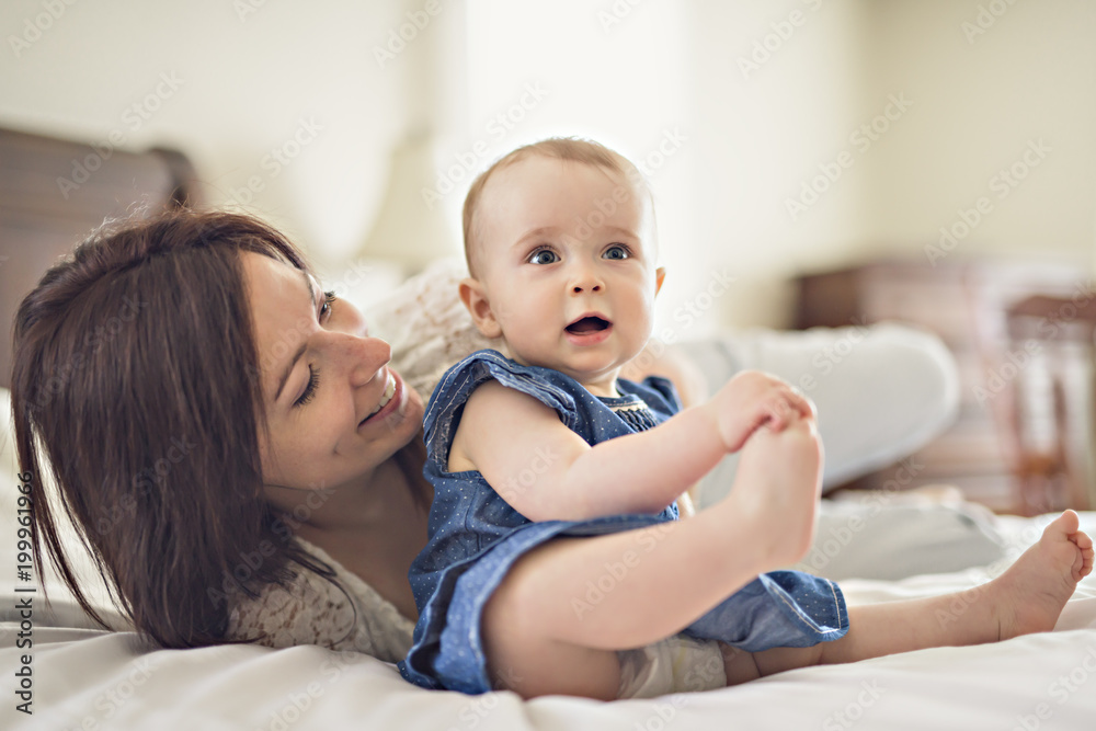 mother playing with her baby in the bedroom