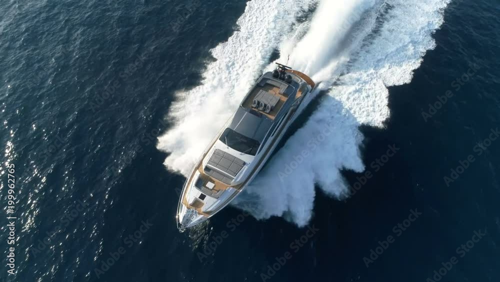 Aerial perpendicular view of a luxury yacht navigating fast.