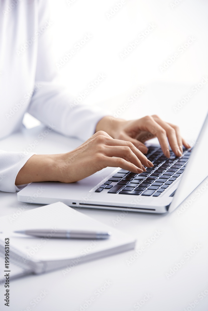 Typing on laptop keyboard. Close-up of a young woman holding brush in her hand and applying makeup. Isolated on light blue background. - obrazy, fototapety, plakaty 