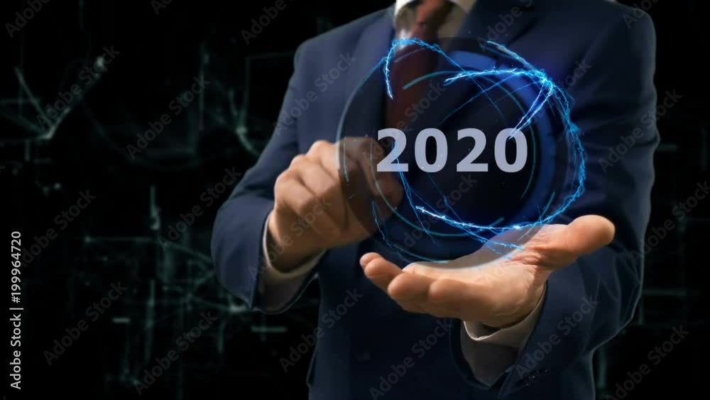 Businessman shows concept hologram 2020 on his hand. Man in business suit with future technology screen and modern cosmic background Businessman shows concept hologram 2020 on his hand. Man in business suit with future technology screen and modern cosmic background