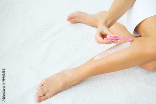 caucasian woman shaving legs with razor