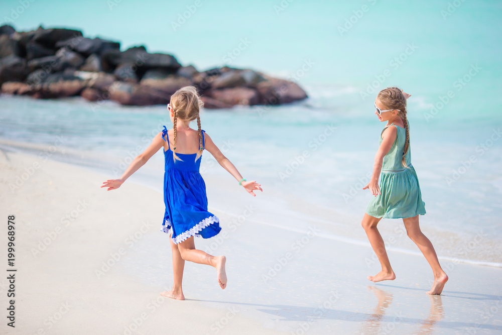Little happy funny girls have a lot of fun at tropical beach playing together. Little happy funny girls have a lot of fun at tropical beach playing together.