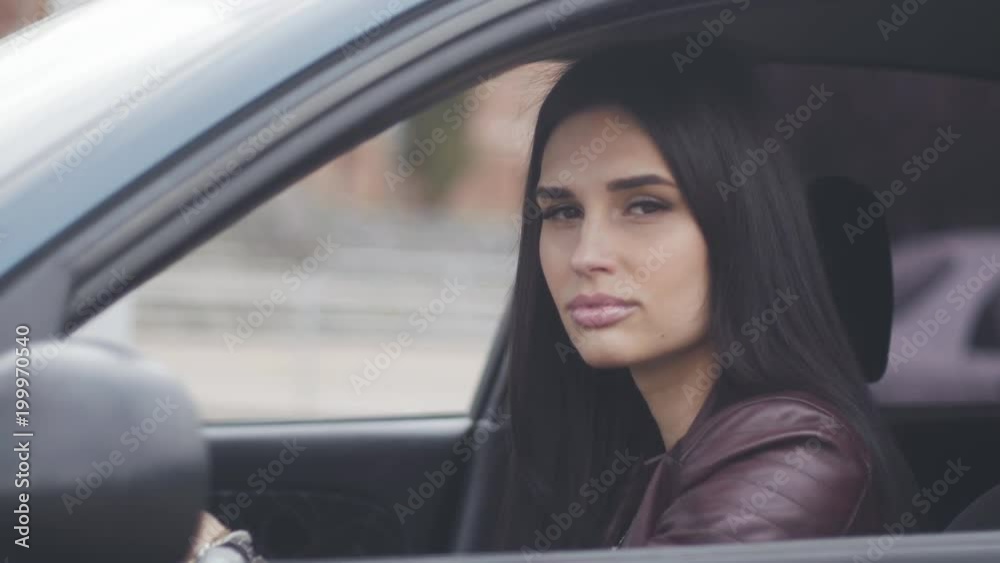 beautiful brunette woman sits in a car on a driver's seat in the city beautiful brunette woman sits in a car on a driver's seat in the city