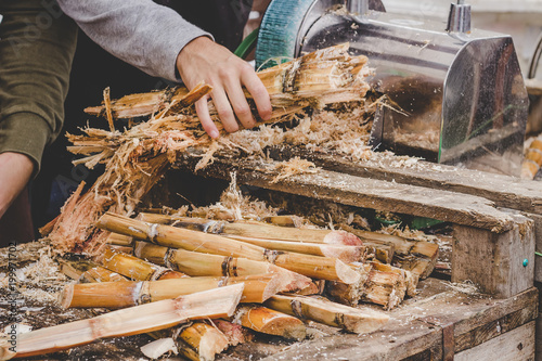 Man queezing sugar cane juice at street food market