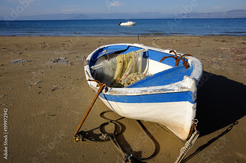 Lonely fisherboat with net and  anachor at the coast of Kavos in Corfu, Greece photo