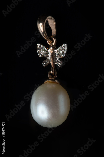 Gold pendant with a pearl on a black background