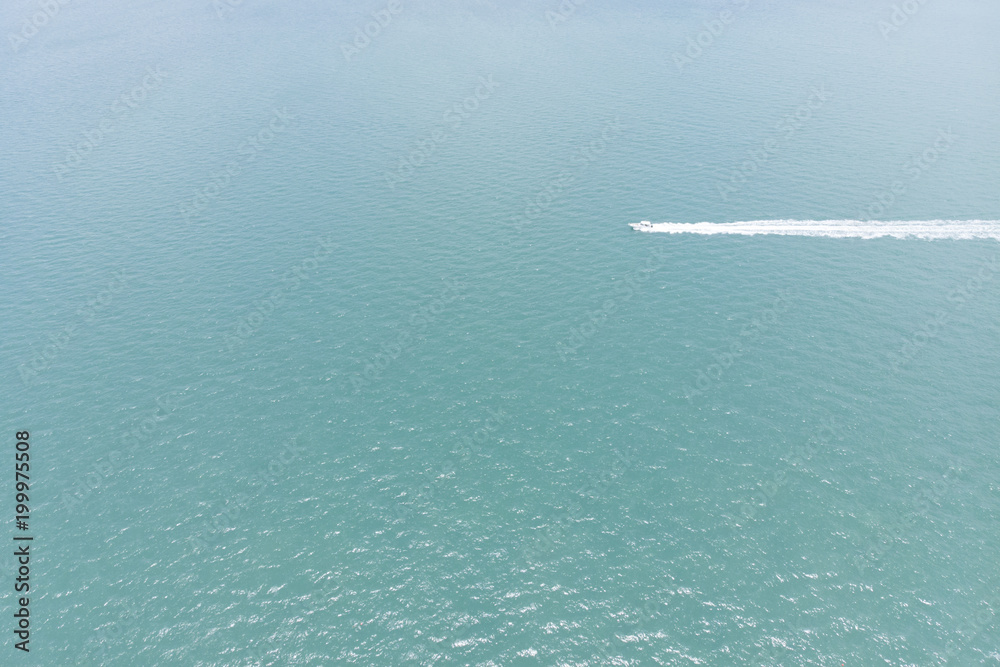 Obraz premium Aerial view of the sea with a motorboat crossing the ocean with white trace