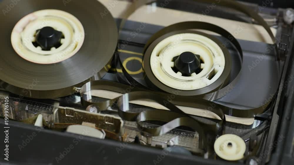 Audio tape loops and tangling in a deck cassette player when the take up spool stops or running slower than the other. Close up 4K static shot. Spinning magnetic tape in tape drive. 