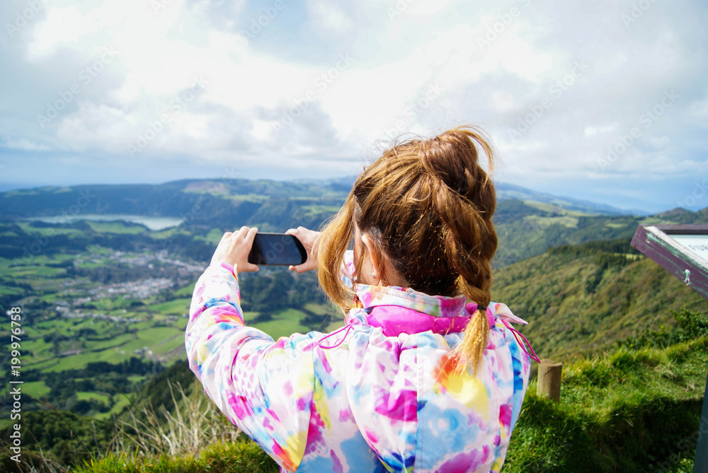 Young woman taking a photo with her mobile phone in Furnas, Azores islands