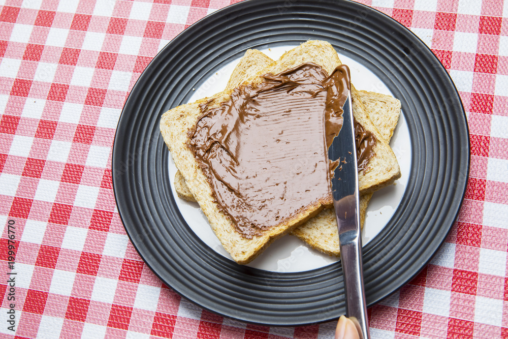 Unknown woman spreading chocolate cream on bread Unknown woman spreading chocolate cream on bread