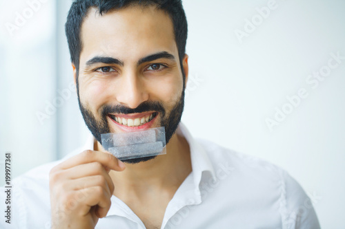 Teeth Whitening. Beautiful Smiling Man Holding Whitening Strip. High Resolution Image