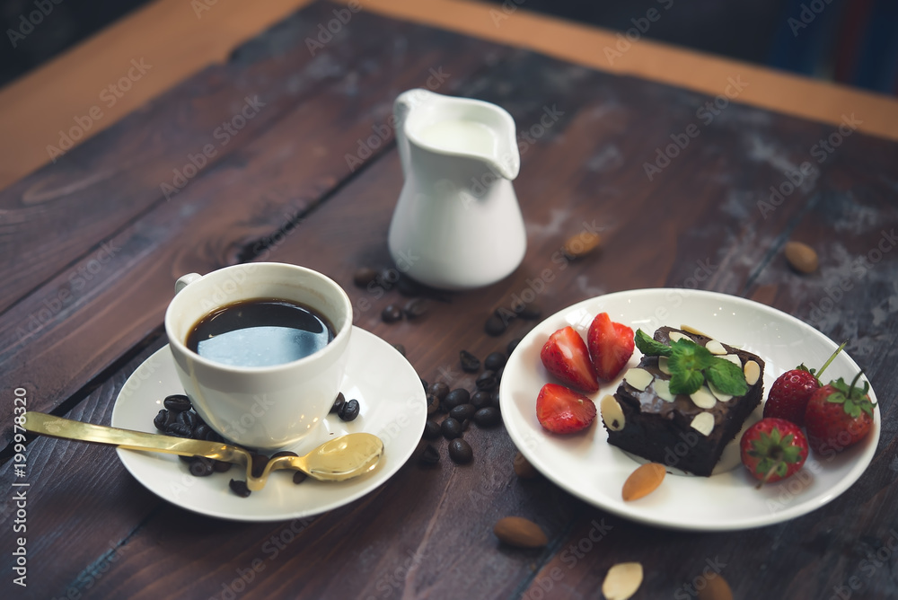 Hot coffee in white cup on wood background,Brownie with Fresh strawberry on white plate Hot coffee in white cup on wood background,Brownie with Fresh strawberry on white plate