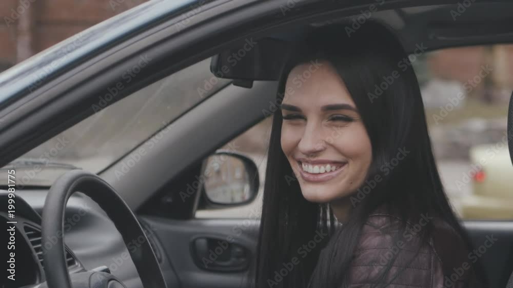 cheerful young woman laughing while sitting in the car