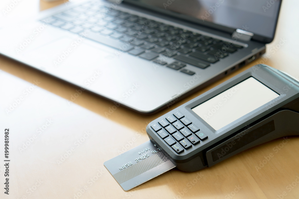 Payment terminal with contactless credit card and laptop, finance concept Payment terminal with contactless credit card and laptop, finance concept