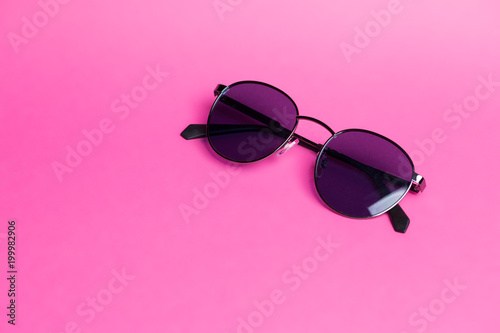 Beautiful sunglasses on pink isolated background close-up