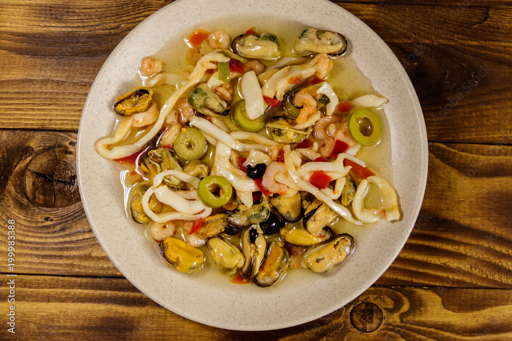 Seafood salad with shrimp, squid and mussels on wooden table Seafood salad with shrimp, squid and mussels on wooden table
