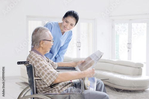 Female nurse talking with old man at home