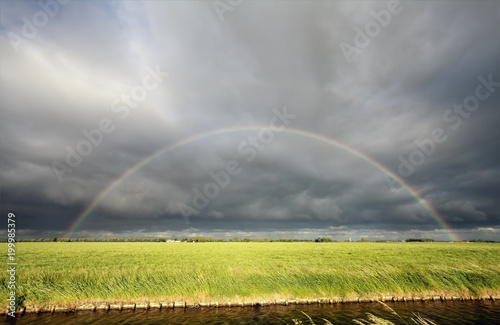rainbow over green meadow and river