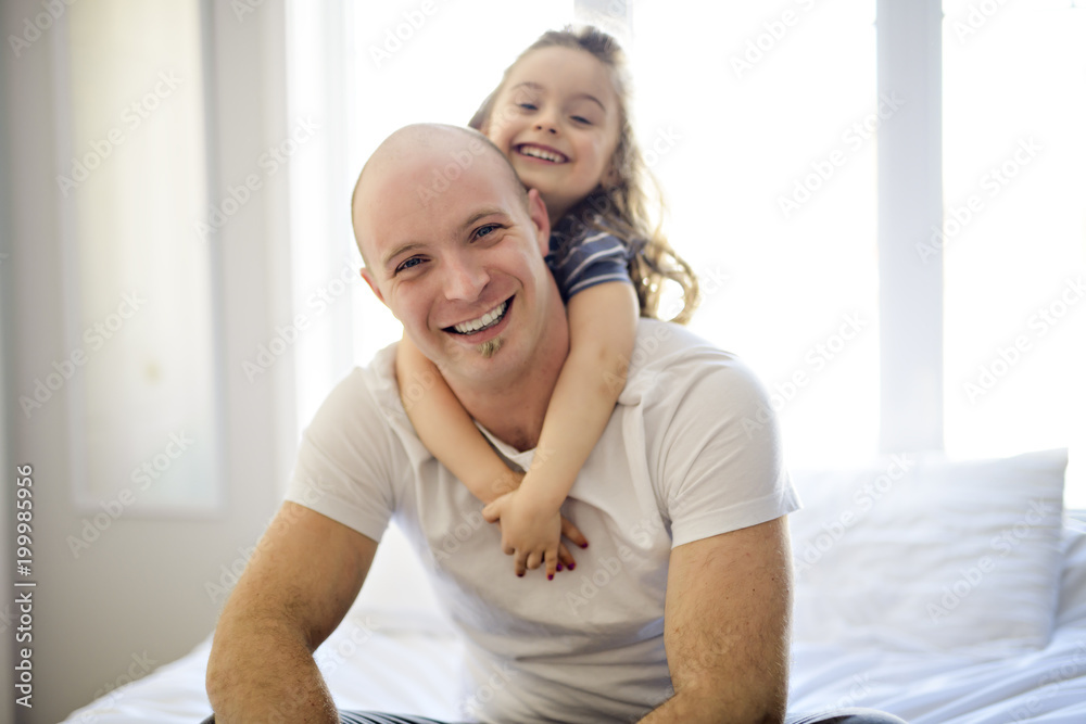 Happy father and daughter having fun together on a bed Happy father and daughter having fun together on a bed