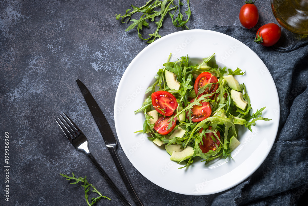 Healthy vegan salad from arugula, avocado and tomatoes. Healthy vegan salad from arugula, avocado and tomatoes.