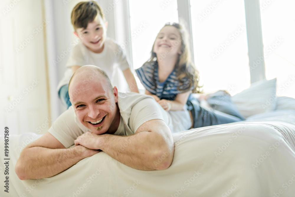 Fototapeta premium Happy father two kids having fun together on a bed