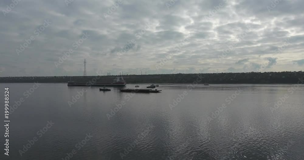 Dry cargo ship and pusher on the fork of a calm river. Summer day. Camera moves in the air near from the ship. Aerial view.