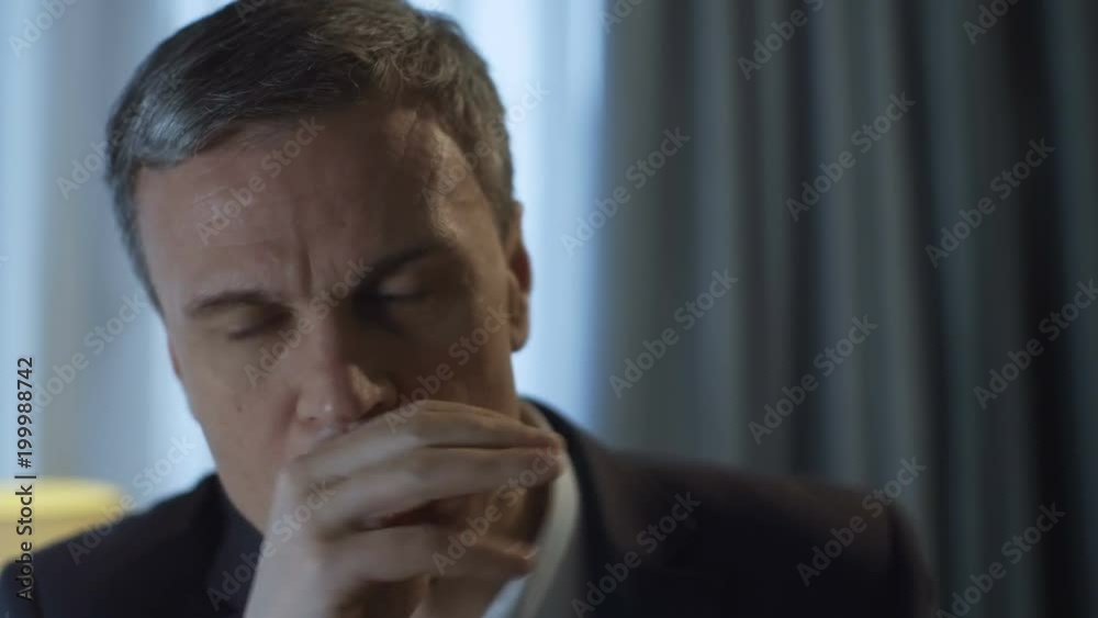 Crop shot of elegant adult man in suit standing in front of mirror in hotel room and rehearsing public speech holding pile of papers. Crop shot of elegant adult man in suit standing in front of mirror in hotel room and rehearsing public speech holding pile of papers.