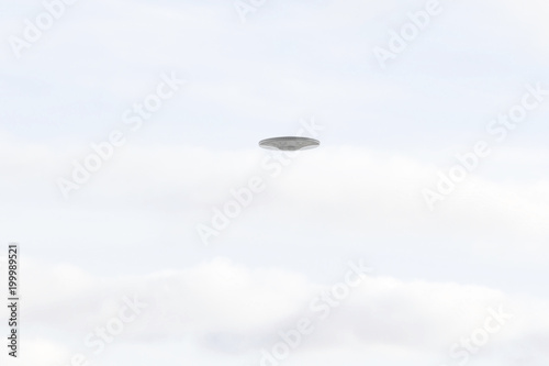UFO Sighting, flying saucer in the white cloudy sky, metal reflective aircraft.