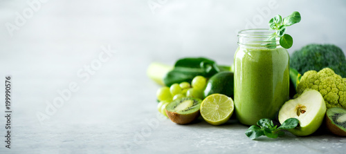 Fotografie, Obraz Glass jar mugs with green health smoothie, kale leaves, lime, apple, kiwi, grapes, banana, avocado, lettuce