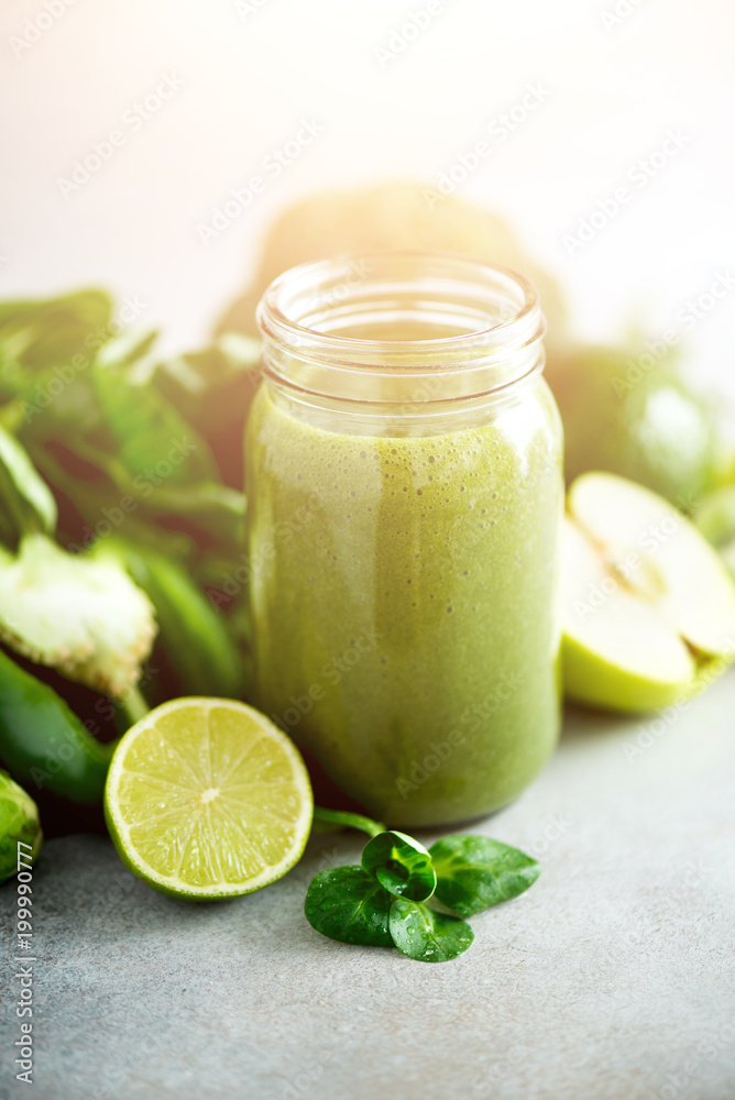Glass jar mugs with green health smoothie, kale leaves, lime, apple, kiwi, grapes, banana, avocado, lettuce. Copy space, sunlight effect. Raw, vegan, vegetarian, detox, alkaline food concept. Glass jar mugs with green health smoothie, kale leaves, lime, apple, kiwi, grapes, banana, avocado, lettuce. Copy space, sunlight effect. Raw, vegan, vegetarian, detox, alkaline food concept.