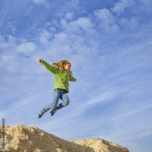 Little pretty girl jumping on sand beach