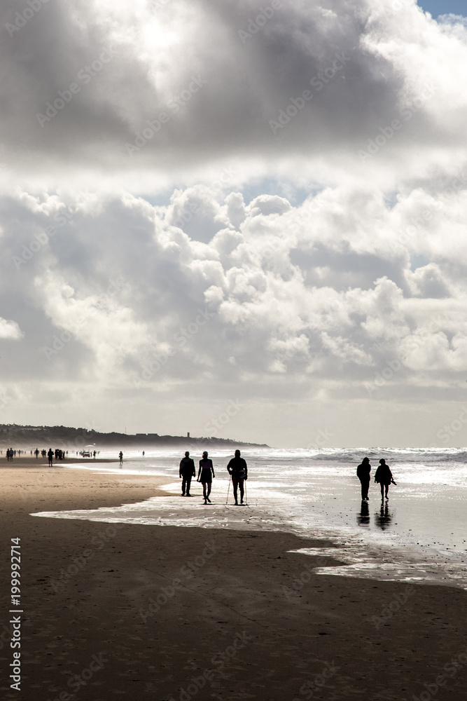 People in the beach under a beautiful cloudy sky