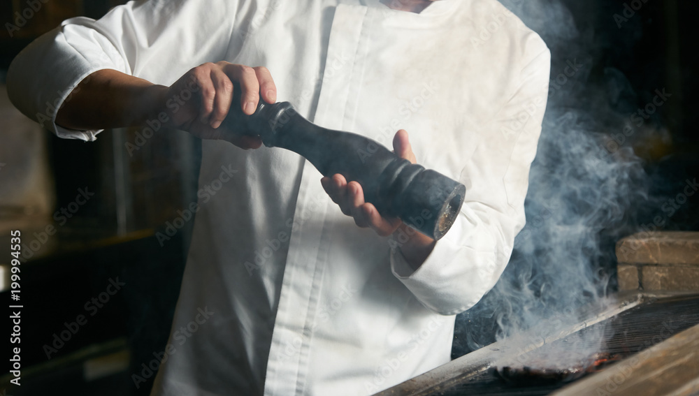 Hand of man take cooking of beef steak meat, Chef cooking beef steak on bbq in restaurant kitchen Hand of man take cooking of beef steak meat, Chef cooking beef steak on bbq in restaurant kitchen
