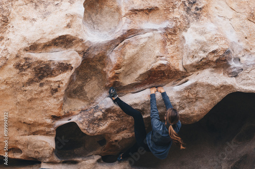 Woman bouldering outside with a heel hook photo