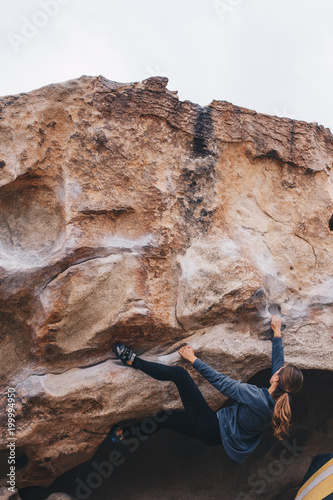 Woman Bouldering outside with a heel hook