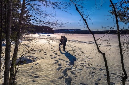 Falun - March 31, 2018: Traveler hiking on the frozen lake at Framby Udde near the town of Falun in Dalarna, Sweden photo