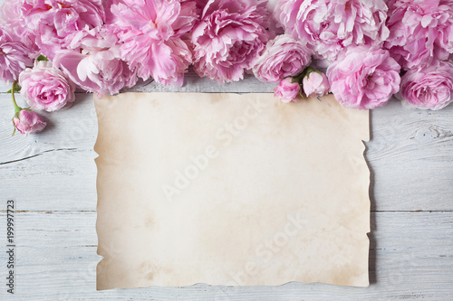 Fototapeta Naklejka Na Ścianę i Meble -  Pink peonies, roses on a wooden background and paper for text congratulations, invitations