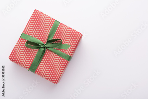 Hands holding wrapped gift box with colored ribbon as a present for Christmas, new year, mother's day, anniversary, birthday, party,  on white background, top view. Present for a colleague at work.