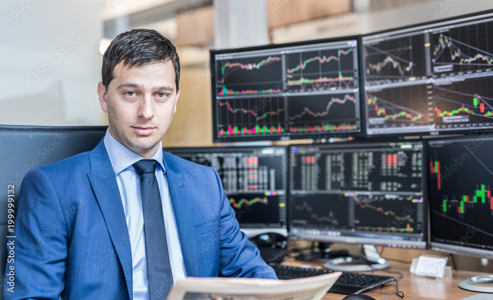 Φωτογραφία Business portrait of confident stocks broker holding a business newspaper in traiding office with multiple computer screens full of index charts and data analyses