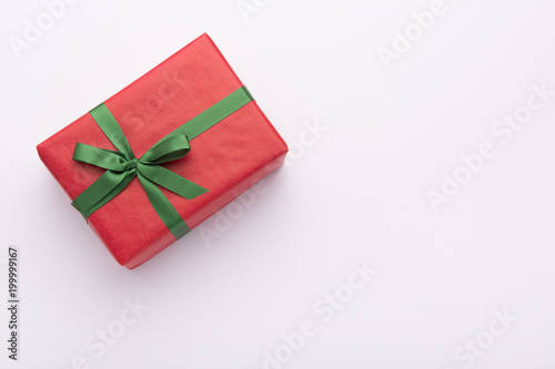 Hands holding wrapped gift box with colored ribbon as a present for Christmas, new year, mother's day, anniversary, birthday, party,  on white background, top view. Present for a colleague at work.