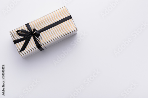 Hands holding wrapped gift box with colored ribbon as a present for Christmas, new year, mother's day, anniversary, birthday, party,  on white background, top view. Present for a colleague at work.