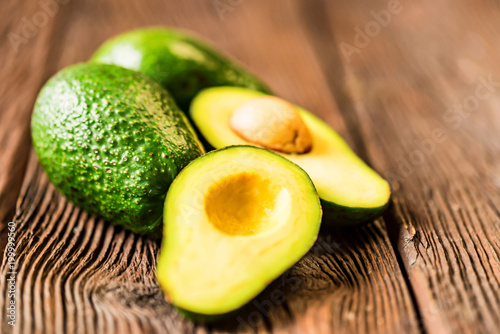 Avocados cut and whole on a wooden background