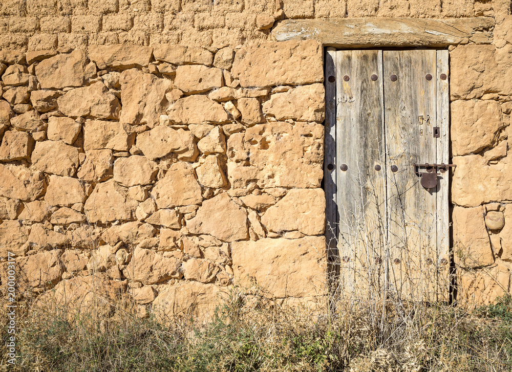 ancient wooden door with a rusty padlock on an antique stone made wall ancient wooden door with a rusty padlock on an antique stone made wall
