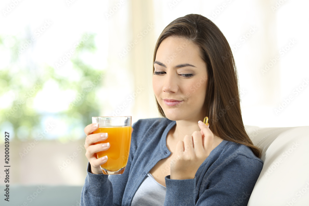 Woman doubting between vitamin pill or orange juice
