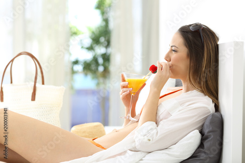 Woman drinking in an hotel room in summer vacations
