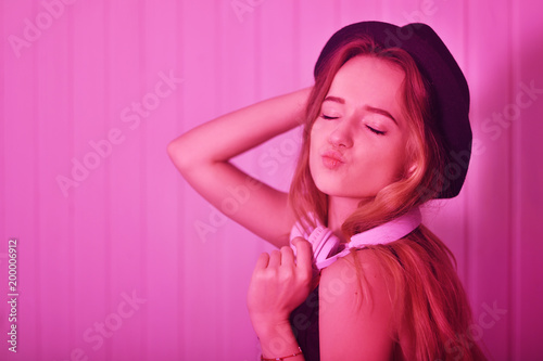 Fashion pretty cool girl in headphones listening to music over pink background. Energy model with long hair. With red lips © MoreThanProd