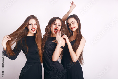 Beautiful young girls with make-up, red lips, pretty face . Womans on white background. Cheerful young womans wearing black dress, looking at camera with joyful and charming smile. Long hair