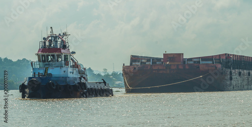 Tugboat pulling heavy loaded barge of black coal in the Mahakam river, Indonesia