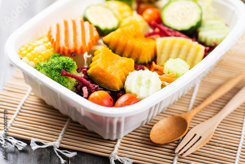 Vegetables salad in a plastic box with wooden spoon and fork, healthy food